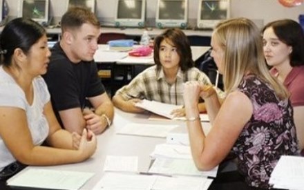 An IEP meeting with four adults and one student at a table in a classroom