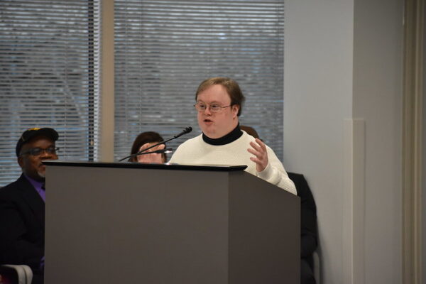 self advocate Frank Stevens speaks from behind a lecturn at a regional budget hearing.