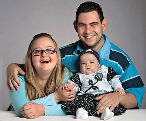 Family portrait of a mother with Down syndrome, a father with a slight disability, and their baby.
