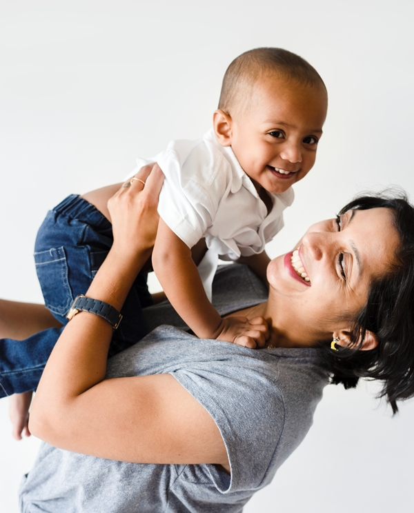 a middle-aged woman of color holds a Black toddler-aged boy.