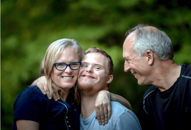 Mom and son with special needs embrace while dad looks on