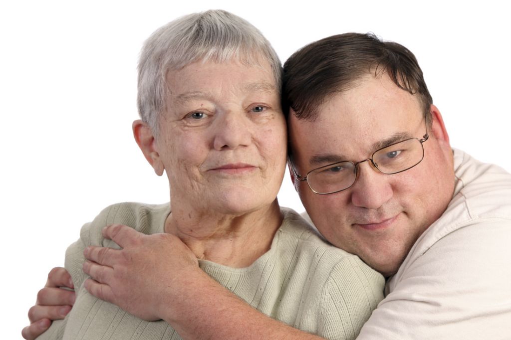 An adult man with IDD embraces his mother around her shoulders