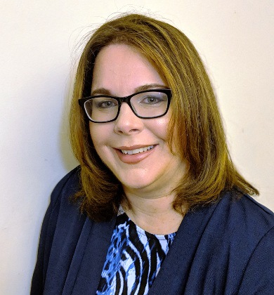 head and shoulders photo of Laura Allen. Laura is a white woman with shoulder length brown hair. She is wearing glasses and a blue blazer over a print blouse.