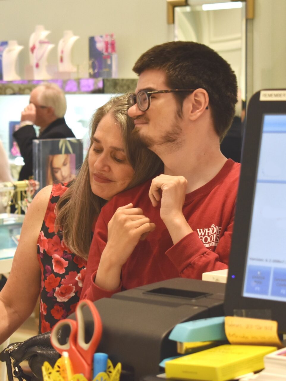 At the checkout counter of a retail store, mom Mary Ford lays her head on the shoulder of her son Christian, who has autism.