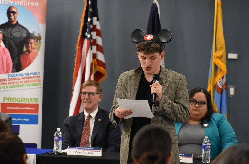 young man wearing Mickey Mouse ears speaks into a microphone at a Candidates Forum event.