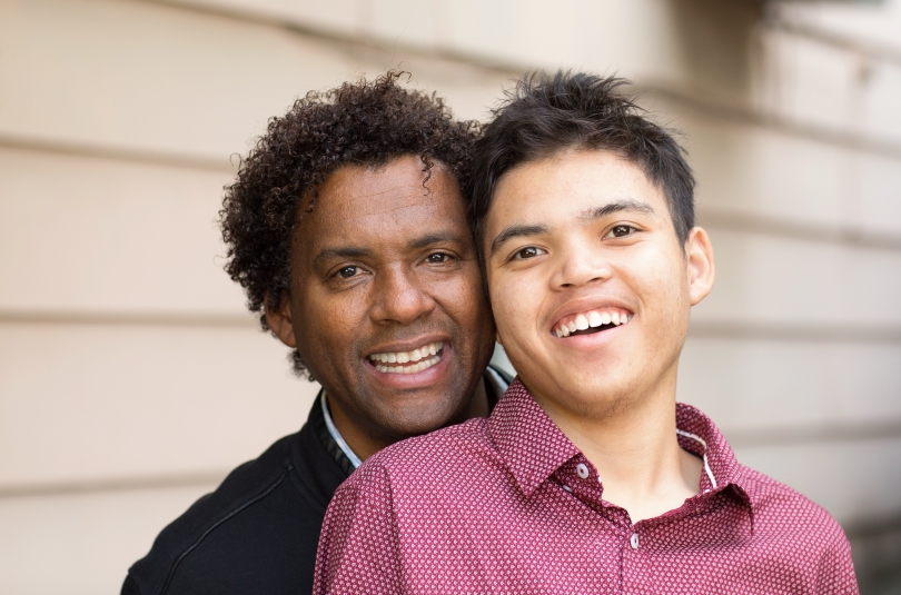 A close up, head and shoulders photo of a black man and his son, smiling.