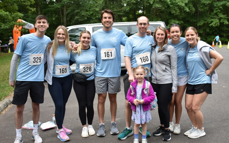 photo of eight runners and walkers, and one young girl in a dress and a pink coat