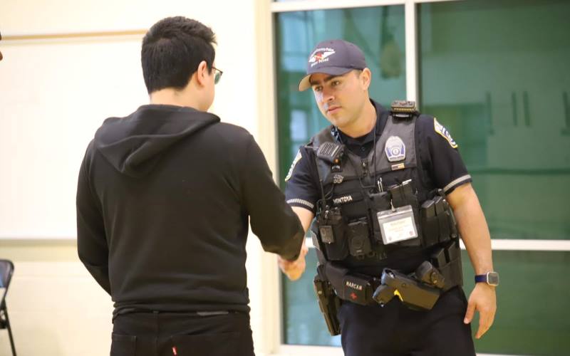 a young man shakes hands with a uniformed police officer