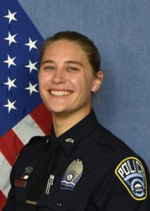 Head and shoulders picture of police officer Madelyn Ernesto, in her uniform, posed in front of an American flag.